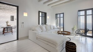 A modern living room with a white sofa, a round coffee table, and a view of the sea through large windows. - House G in Kardiani Tinos (Tinos)