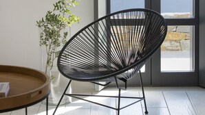 A modern room with a black wireframe chair, a small wooden table, and a potted plant. - House G in Kardiani Tinos (Tinos)