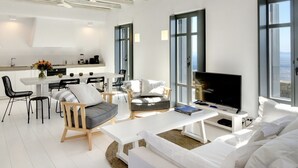 A modern living room with a large TV, white furniture, and a view of the sea through large windows. - House Y in Kardiani Tinos (Tinos)