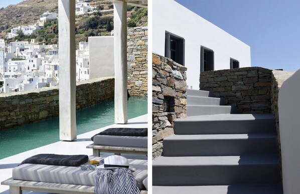 A coastal hotel with white buildings, a stone staircase, and a pool area with lounge chairs and amenities. - House Y in Kardiani Tinos (Tinos)
