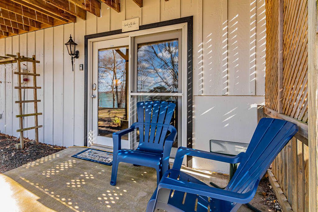 A wooden exterior with a door, two blue chairs, and a ladder.