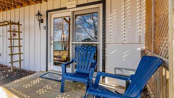 A wooden exterior with a door, two blue chairs, and a ladder.