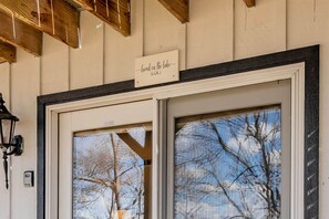 Una puerta con un letrero que dice 'Lived on the lake LOL' y una vista de árboles desnudos a través de la ventana.