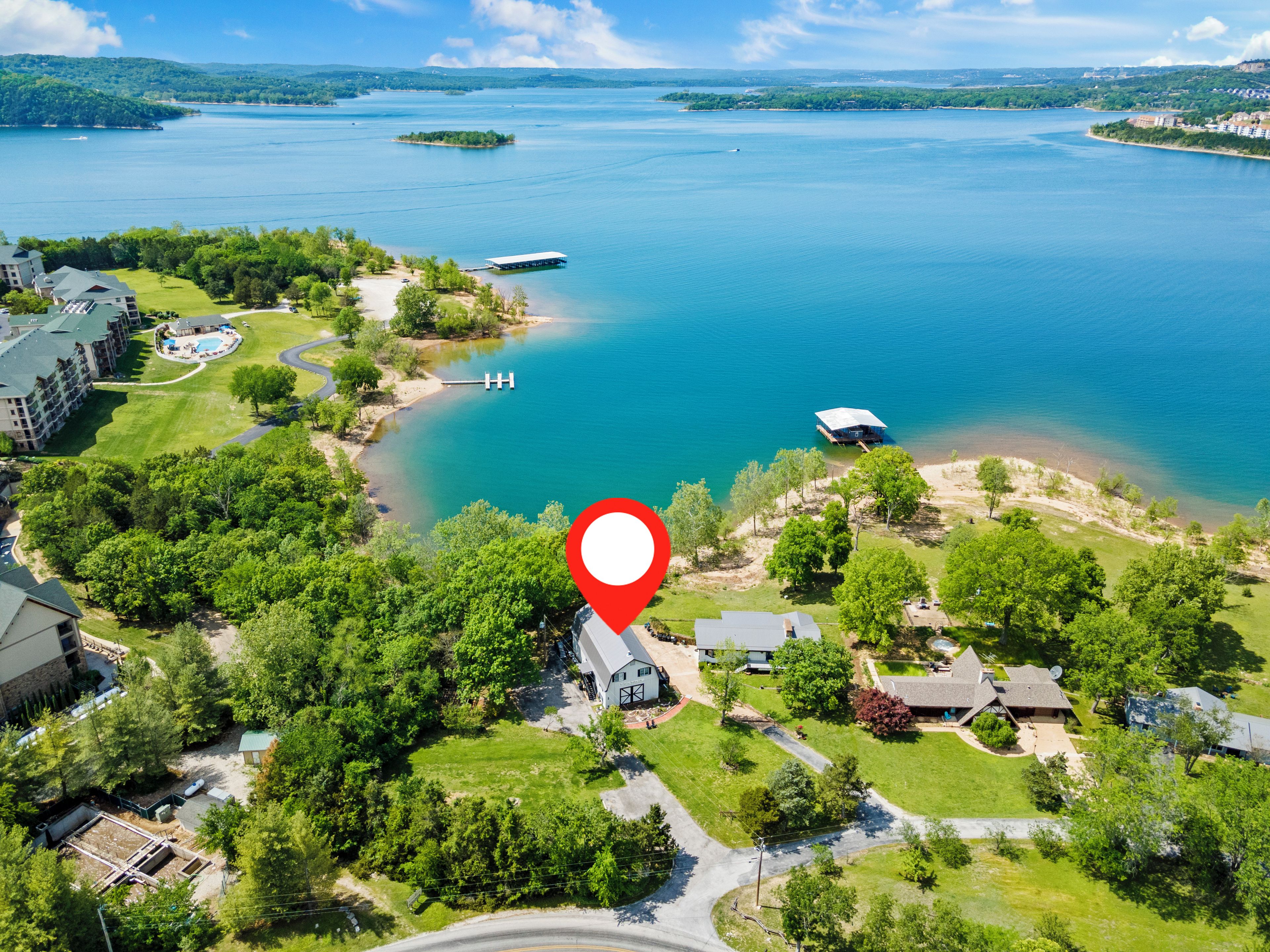 An aerial view of a lakeside property with a marina, a golf course, and residential buildings.