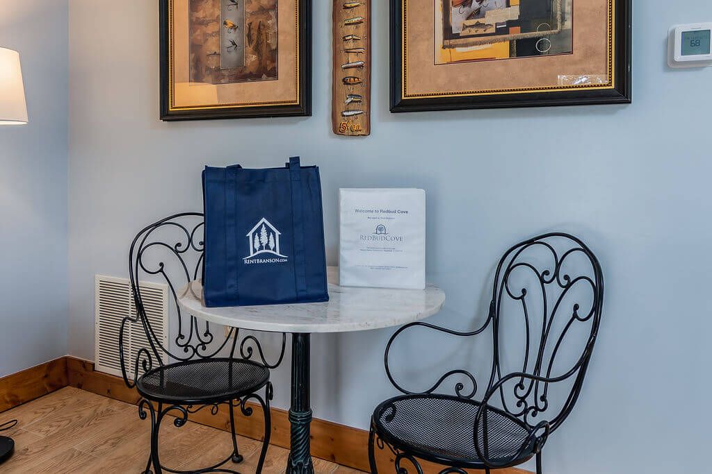 A small table with two chairs, a framed picture, a framed fish wall art, and a welcome sign.