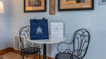 A small table with two chairs, a framed picture, a framed fish wall art, and a welcome sign.