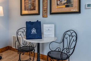 A small table with two chairs, a framed picture, a framed fish wall art, and a welcome sign.