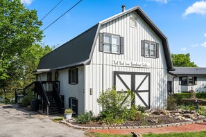 A white building with a black staircase and a sign that reads "Red Bud Cove Barnhouse Suites."