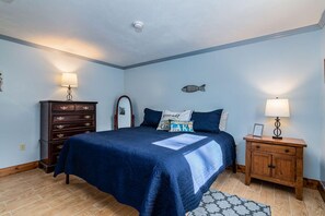 Un dormitorio con cama, cómoda, mesita de noche, lámpara y decoración en la pared.