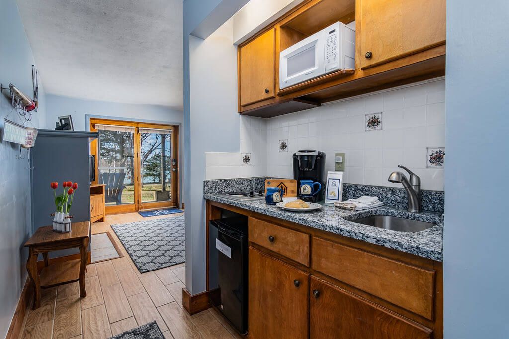 A compact kitchen with wooden cabinets, a microwave, a coffee maker, and a sink.