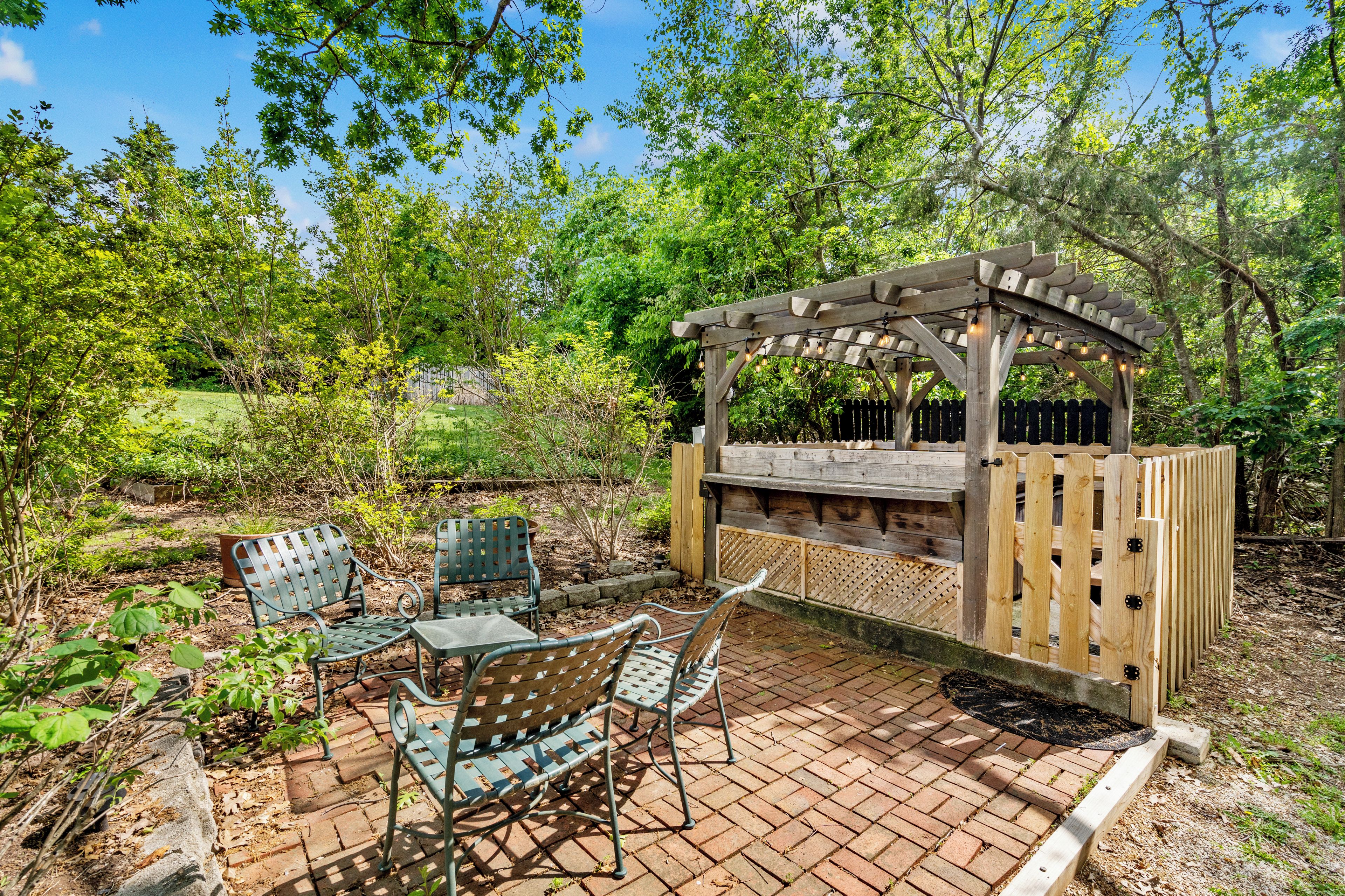 Un espace extérieur aménagé en patio, avec une pergola, des sièges et un sol en briques.
