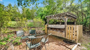 Un espace extérieur aménagé en patio, avec une pergola, des sièges et un sol en briques.