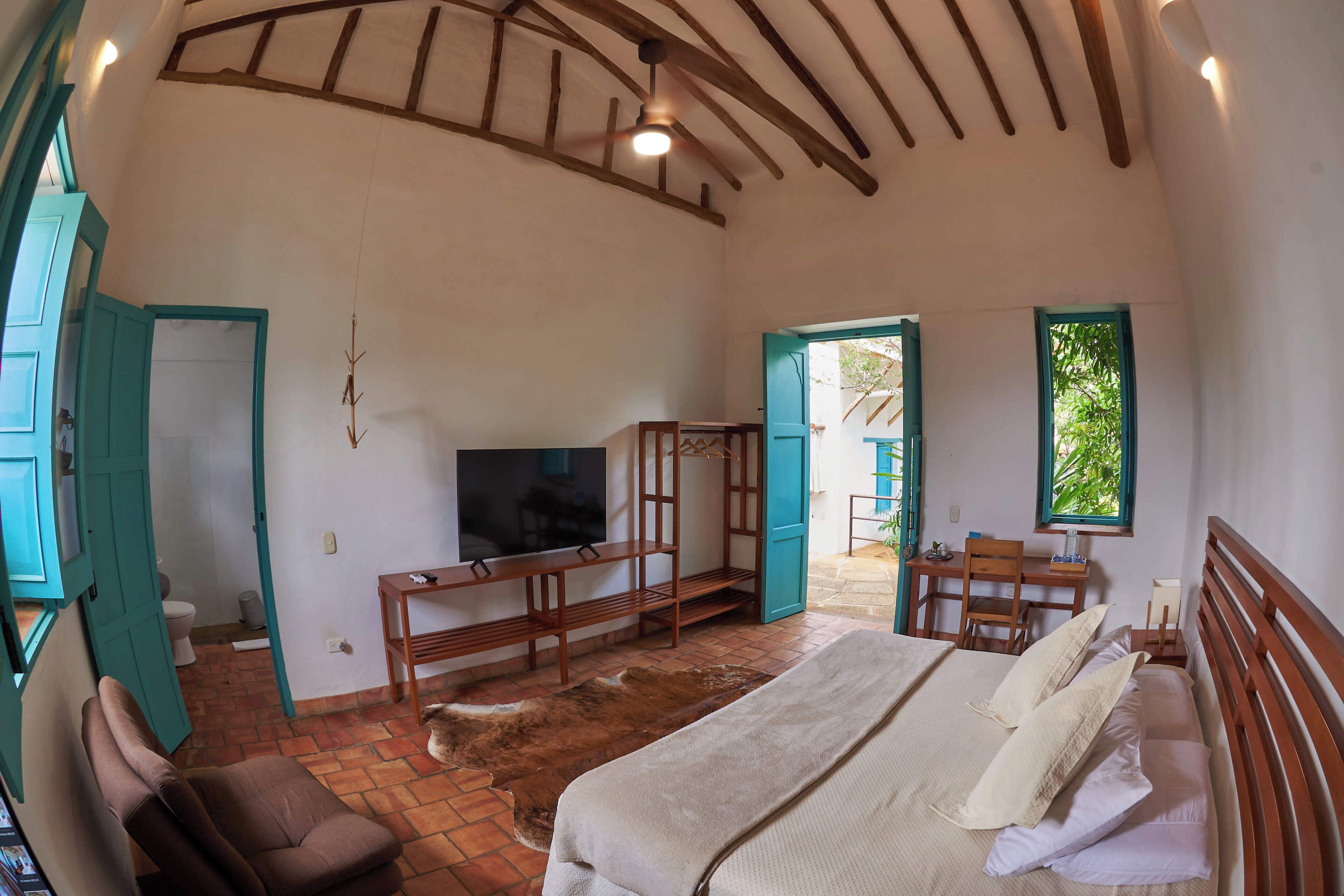 Una habitación con cama, televisión, escritorio y silla.