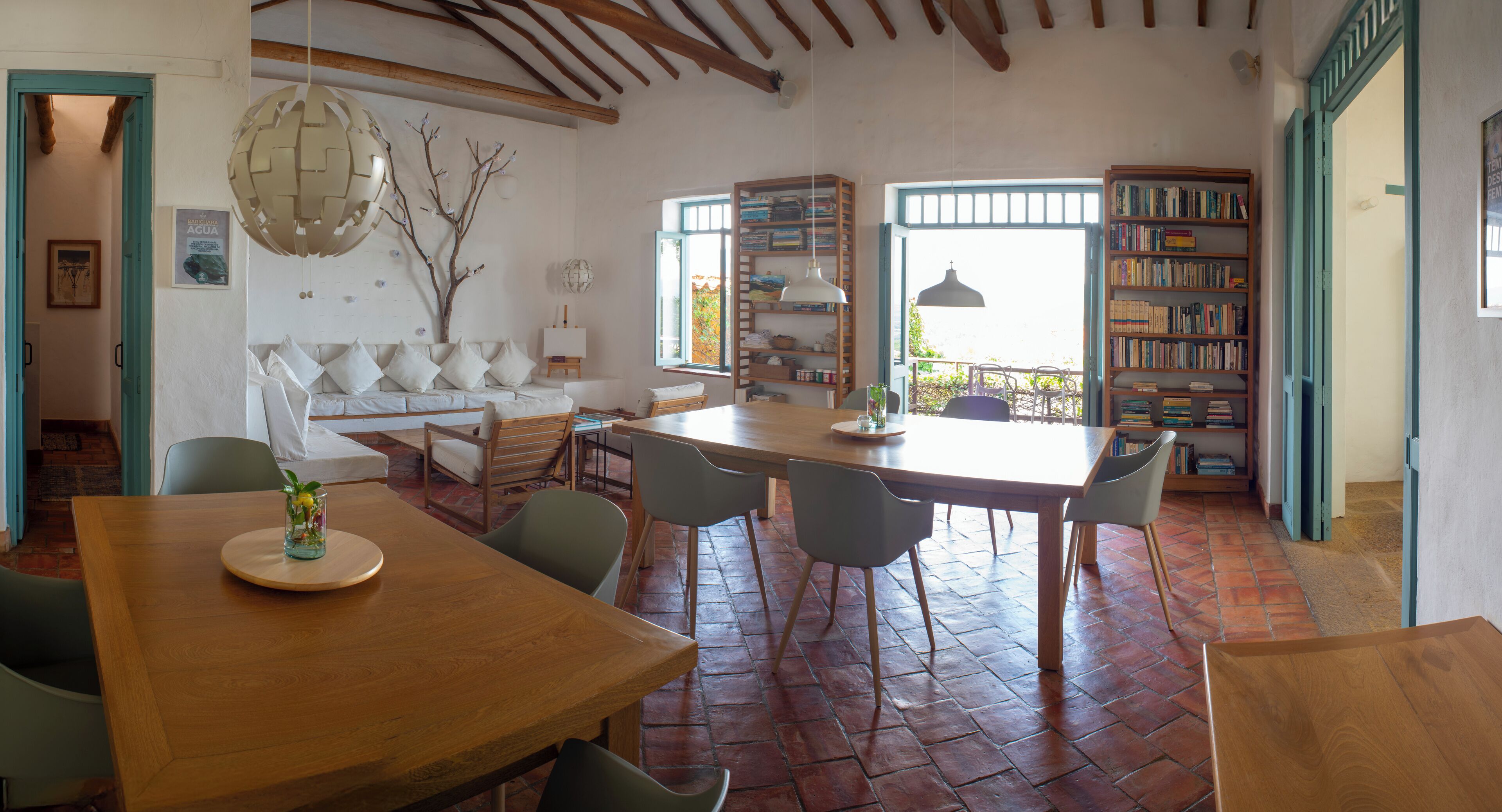 A spacious dining area with a wooden table and chairs, a sofa, and a bookshelf.