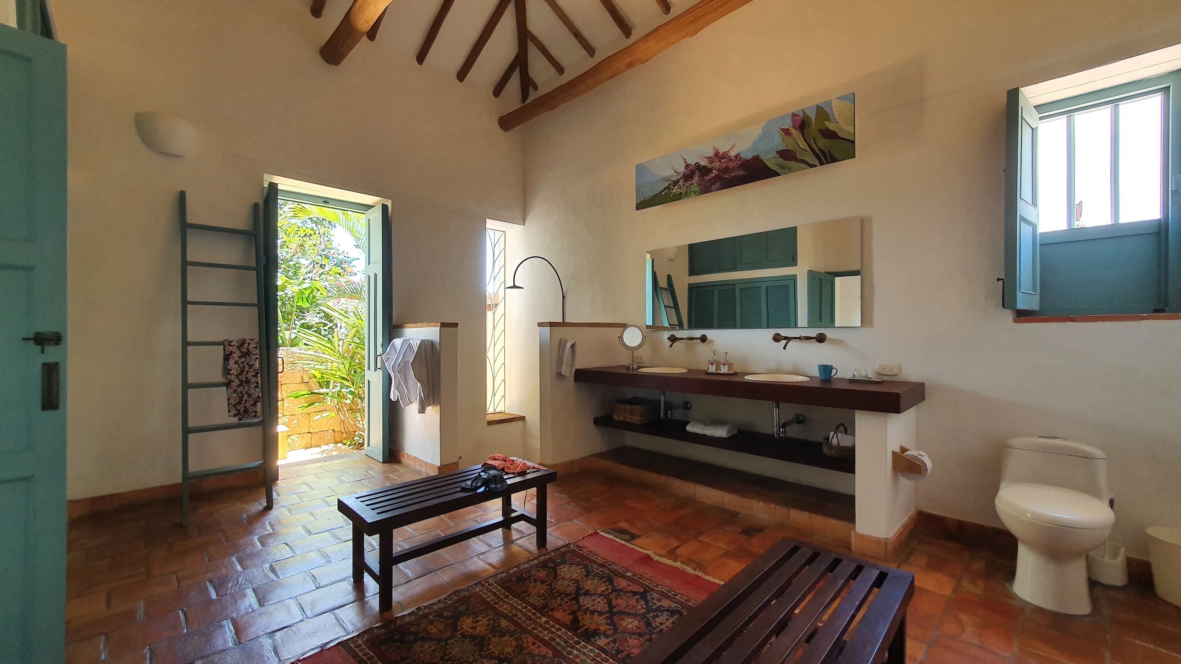 Un baño espacioso con un banco de madera, un lavabo con espejo y un inodoro.