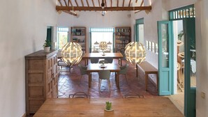 Un comedor amplio con una mesa y sillas de madera, techo alto con vigas a la vista y piso de baldosas.