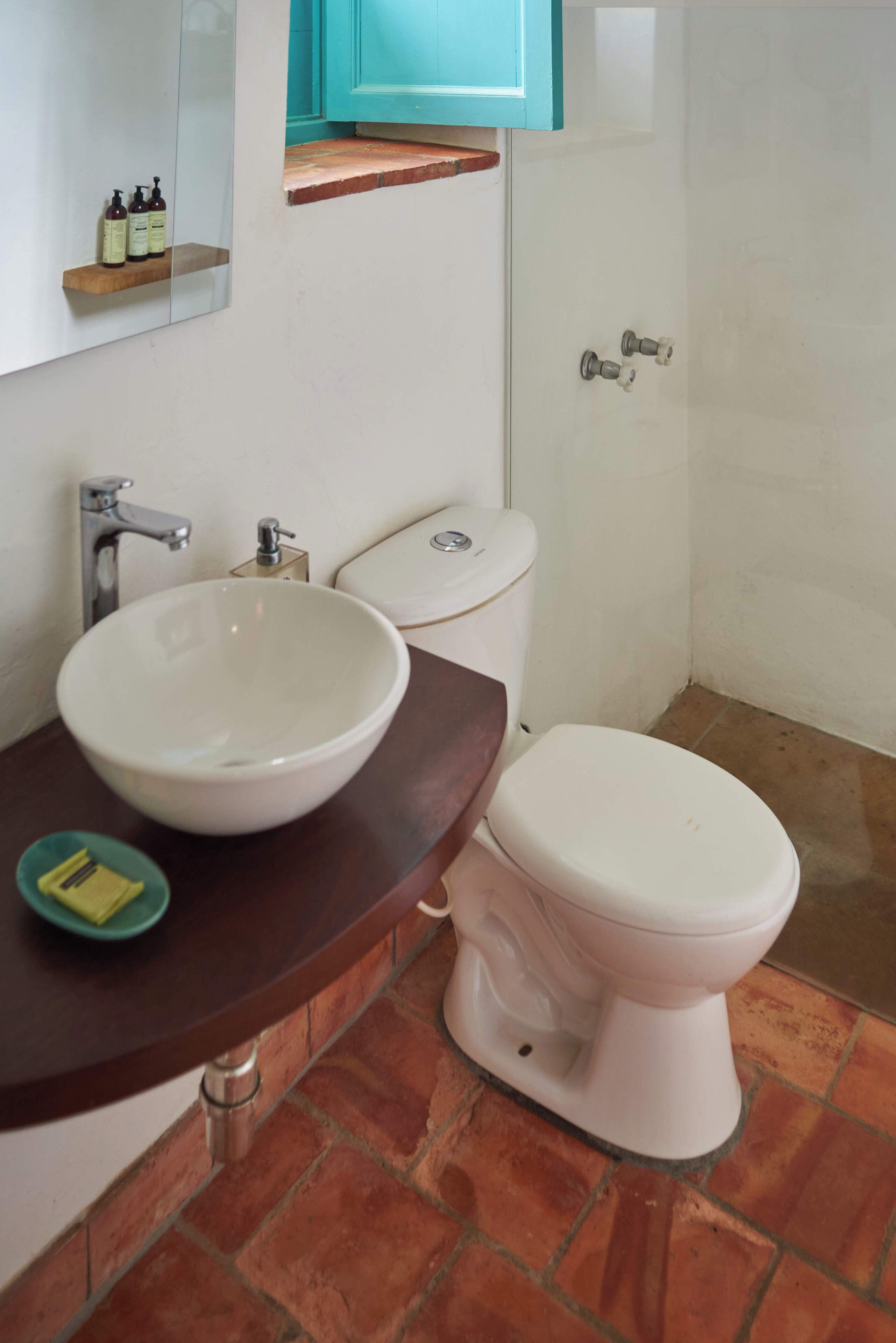 Une salle de bain avec un lavabo blanc, des toilettes et un miroir au-dessus du lavabo.