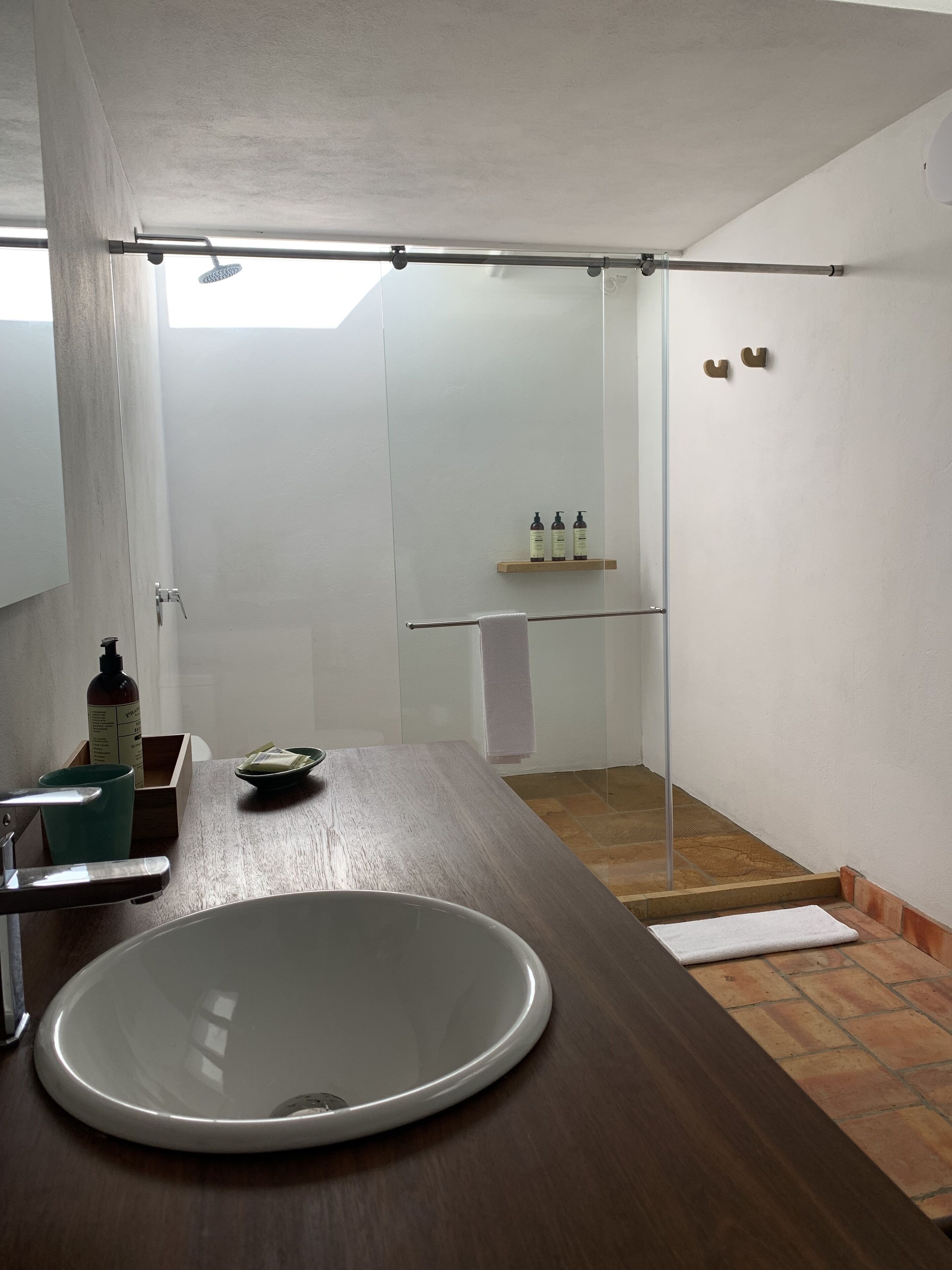 Un baño con un lavamanos grande, cabina de ducha de vidrio y tocador de madera.
