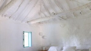 Une chambre à coucher avec un lit, une commode en bois, un tapis en peau de vache, une fenêtre et un plafond blanc.
