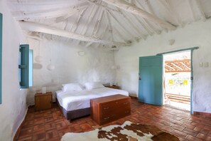 Quarto com cama, cómoda de madeira e tapete de couro.