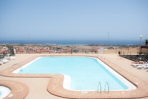 Una piscina con vista al océano y un paisaje urbano al fondo.