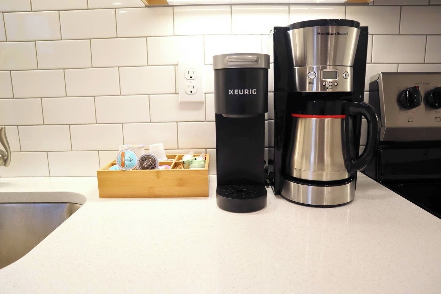 Eine Kaffeemaschine von Keurig und ein Keurig-Reisebecher auf einer Küchenarbeitsplatte.