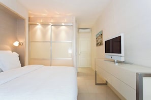 Ein Hotelzimmer mit Bett, Fernseher, Kleiderschrank und einer Schiebetür.