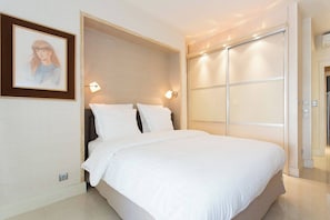 A modern bedroom with a large bed, a framed picture on the wall, and a sliding door closet. - Martinez hotel area: 2 beds/2 baths (Cannes)