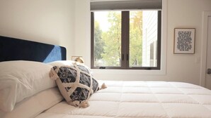 A bedroom with a bed, a window, and a motivational quote on the wall. - Stunning Downtown Condo: Capri 106 (Traverse City)
