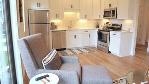A modern kitchen with white cabinets, stainless steel appliances, and a central island. - Stunning Downtown Condo: Capri 106 (Traverse City)
