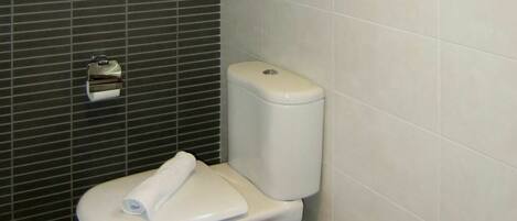 A bathroom with a toilet, a towel, and a window.
