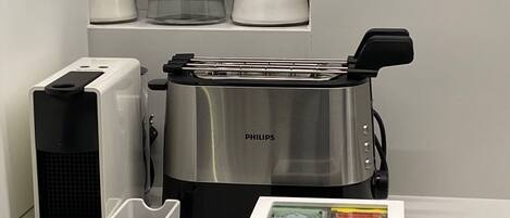 A kitchen with a Philips toaster, a Krups coffee maker, and a box with a heart decoration.