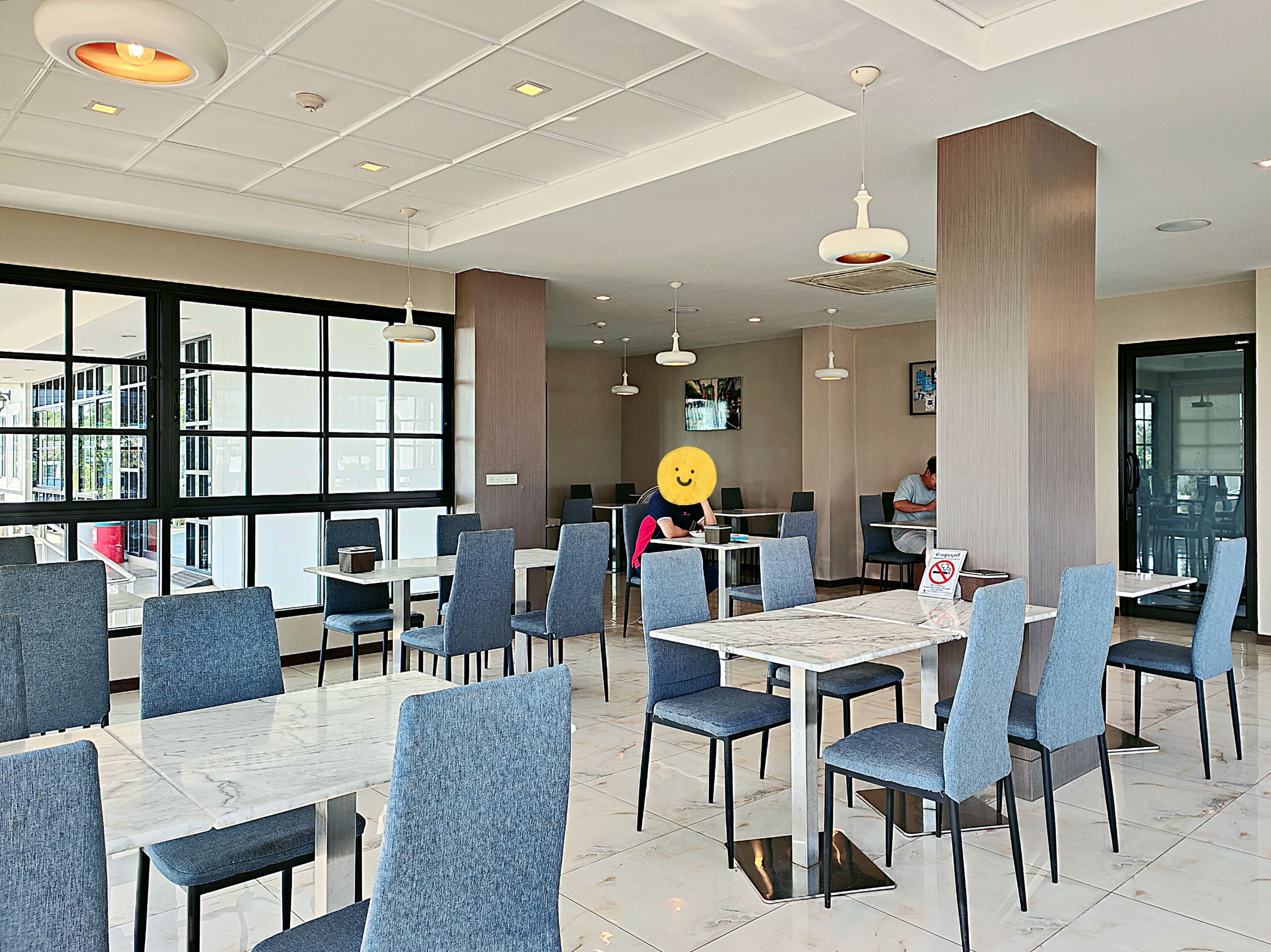 A modern restaurant with marble-topped tables and blue upholstered chairs.