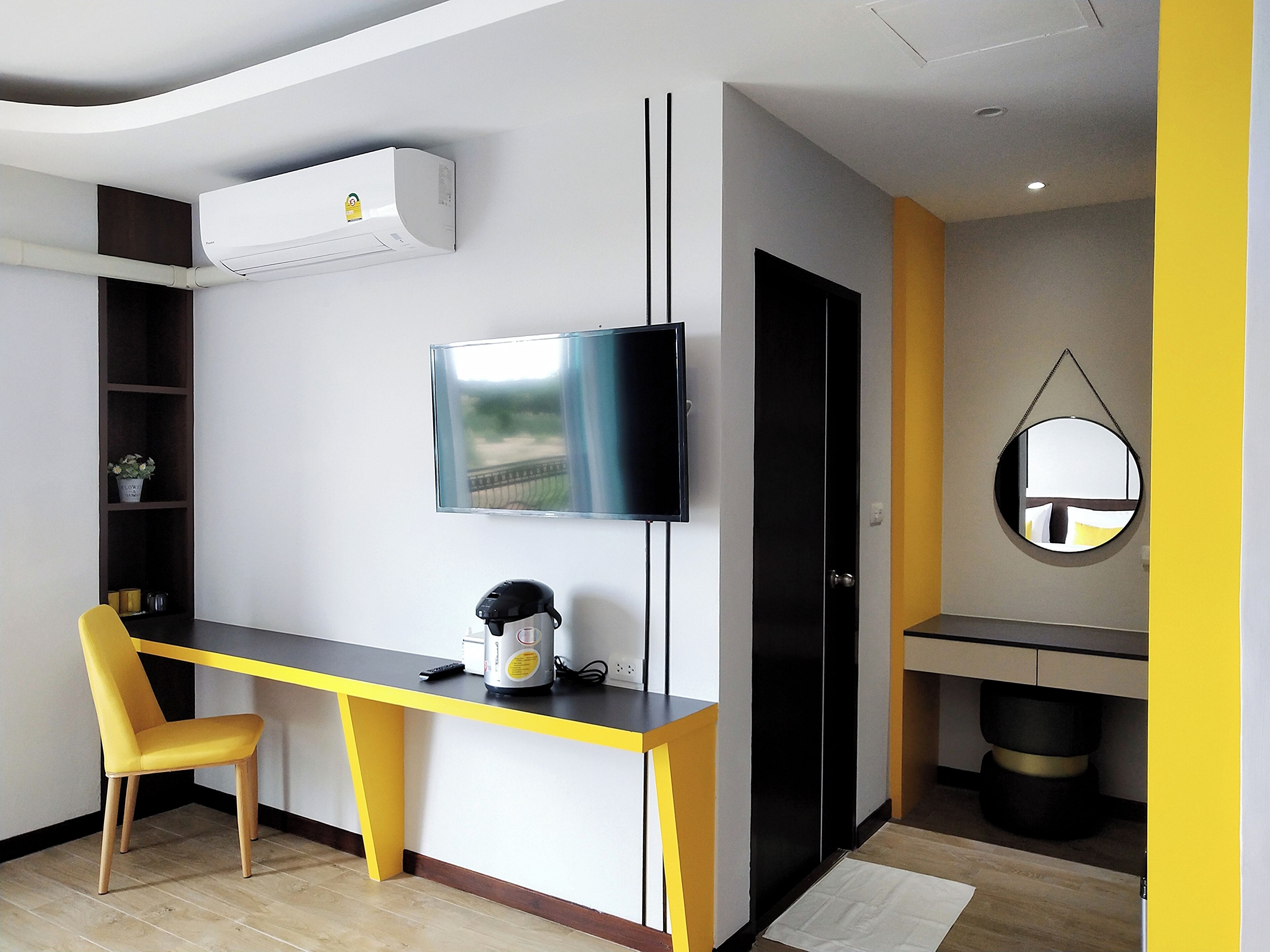 Una habitación moderna con escritorio, silla, televisor y espejo.