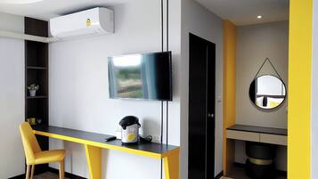 Una habitación moderna con escritorio, silla, televisor y espejo.