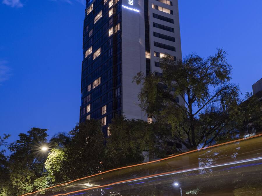 A tall building with illuminated windows and a sign at the top.