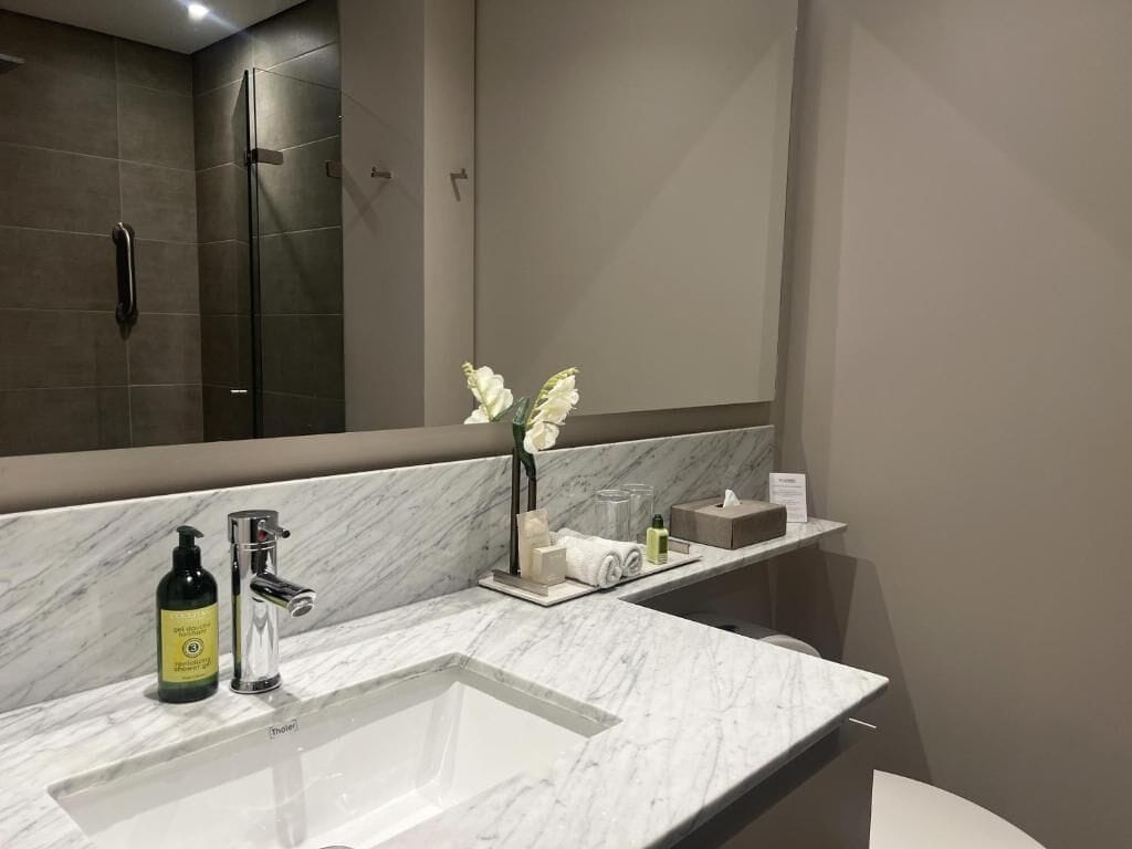 A bathroom with a marble sink, a glass shower enclosure, and a mirror.