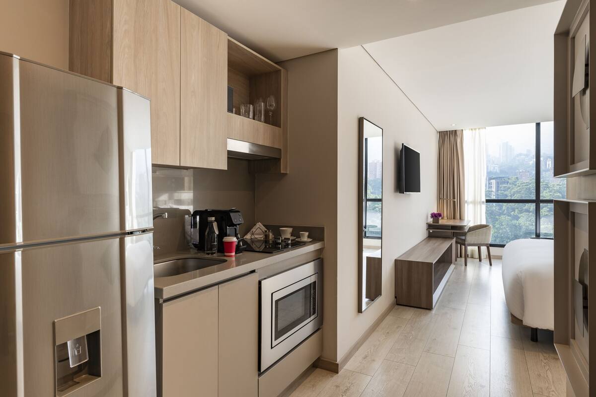 Una cocina moderna con horno empotrado y microondas, una cafetera y un comedor con vistas a la ciudad.
