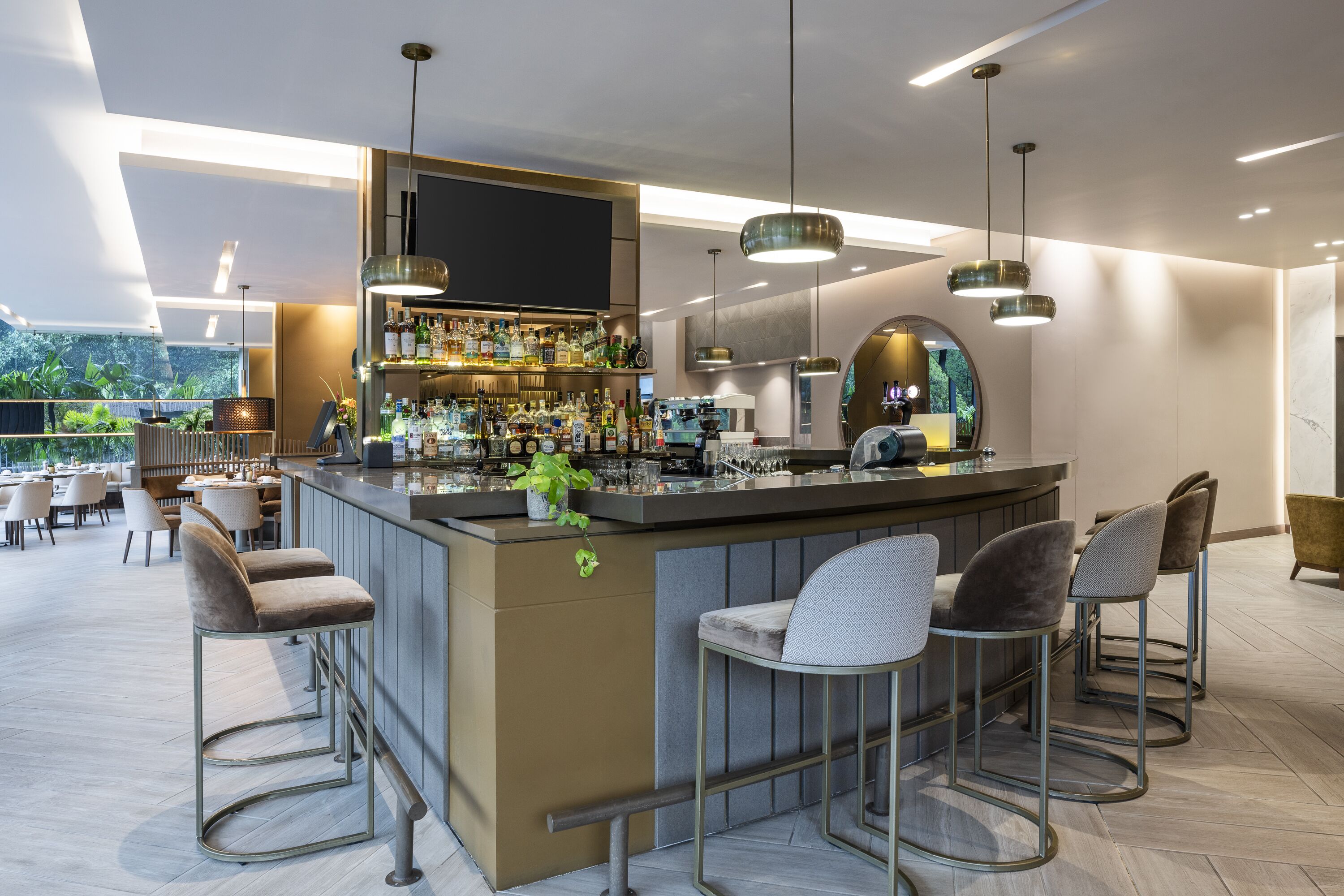 A modern bar area with a counter, bar stools, and a variety of bottles.