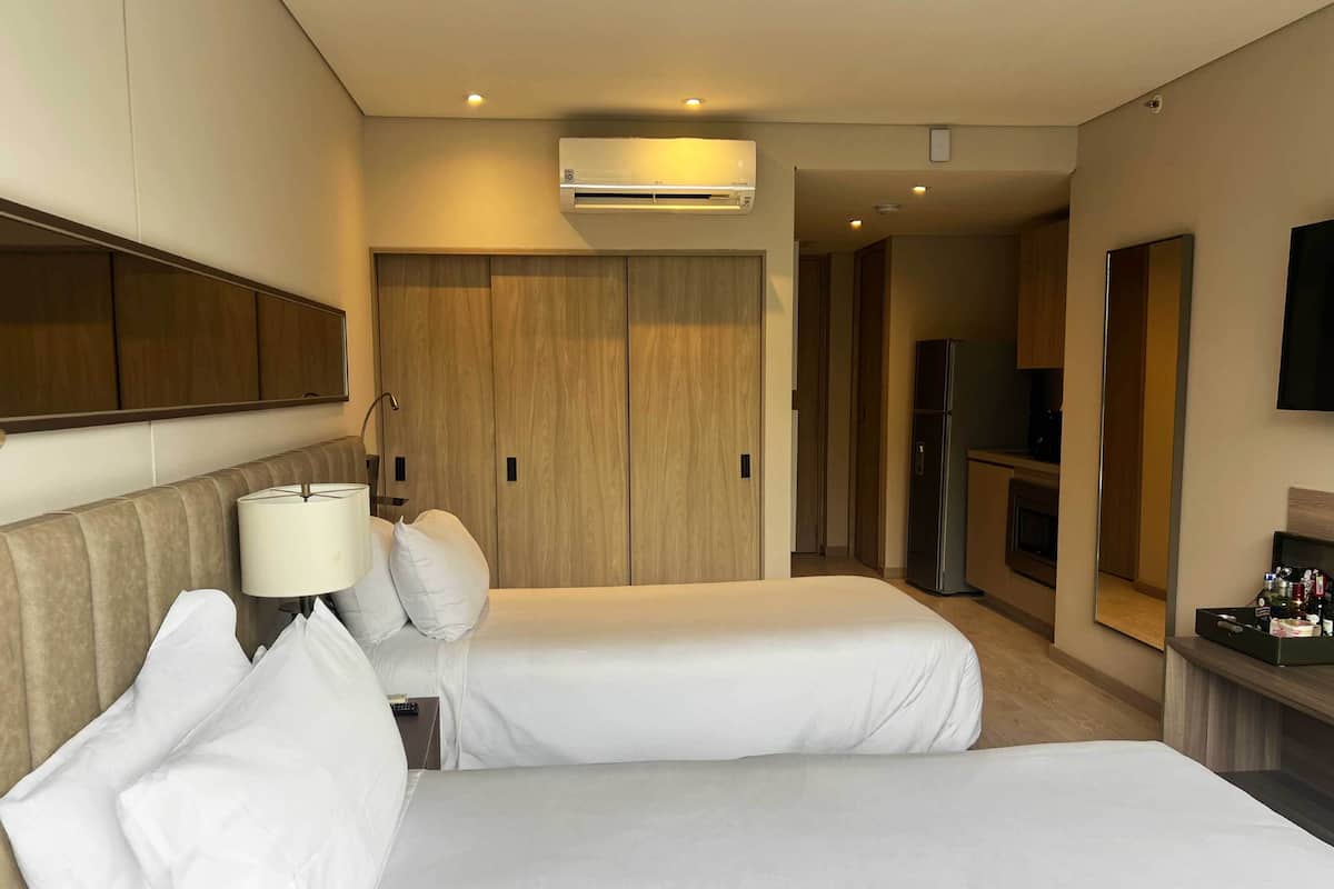 Una habitación de hotel con dos camas, televisión, minibar y armario.