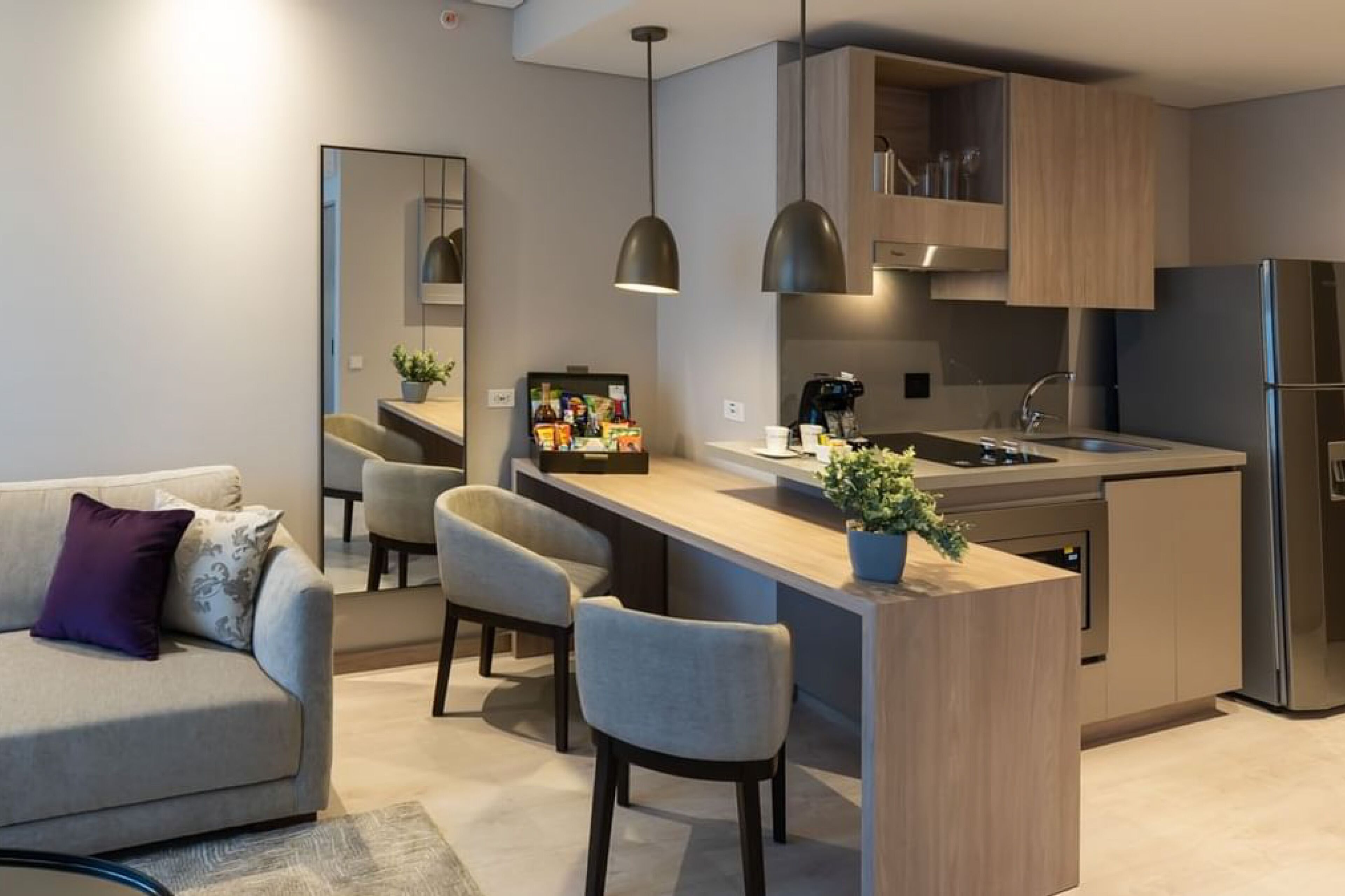 A modern kitchen with a central island, bar stools, and a built-in refrigerator.