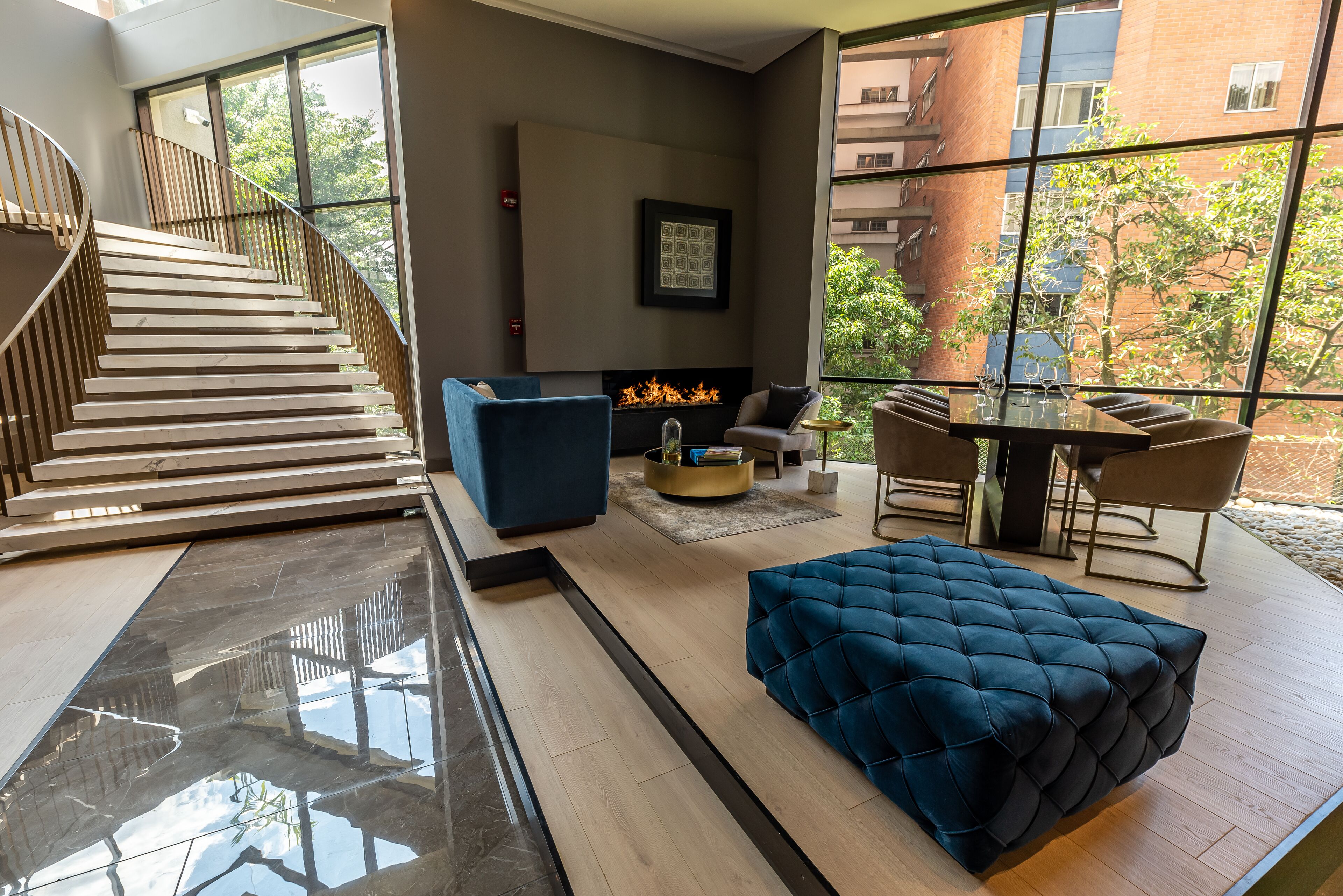 Ein modernes Interieur mit Treppe, einem blauen Sofa, einem runden Couchtisch und einem Kamin.