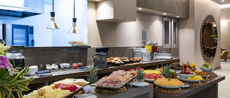 Un bufé con una variedad de alimentos, entre ellos frutas, quesos y carnes.