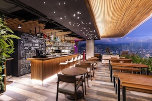 Un área de bar moderna con techo de madera, taburetes y vistas a la ciudad.