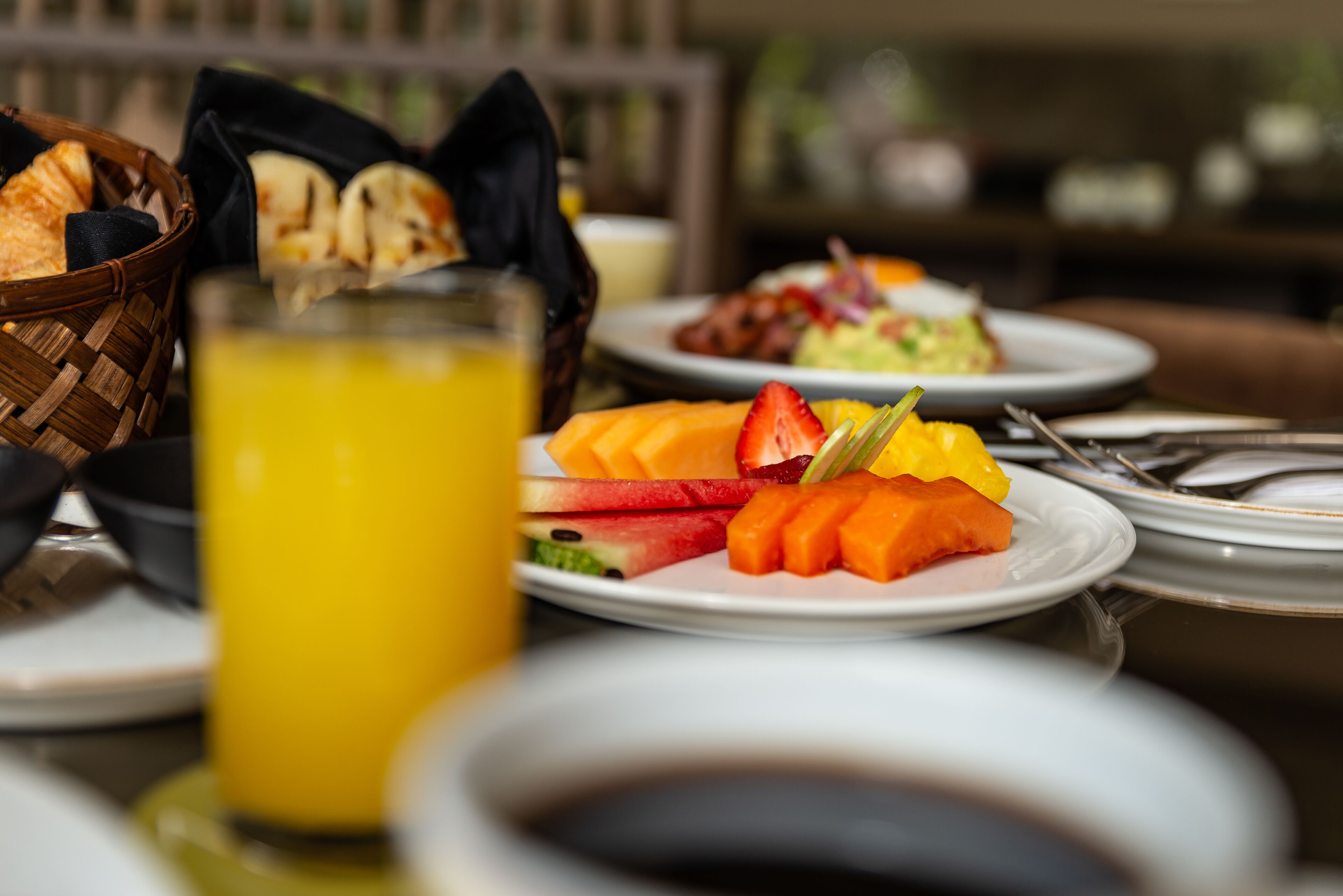 Una colazione con diversi tipi di frutta e un bicchiere di succo d'arancia su un tavolo.