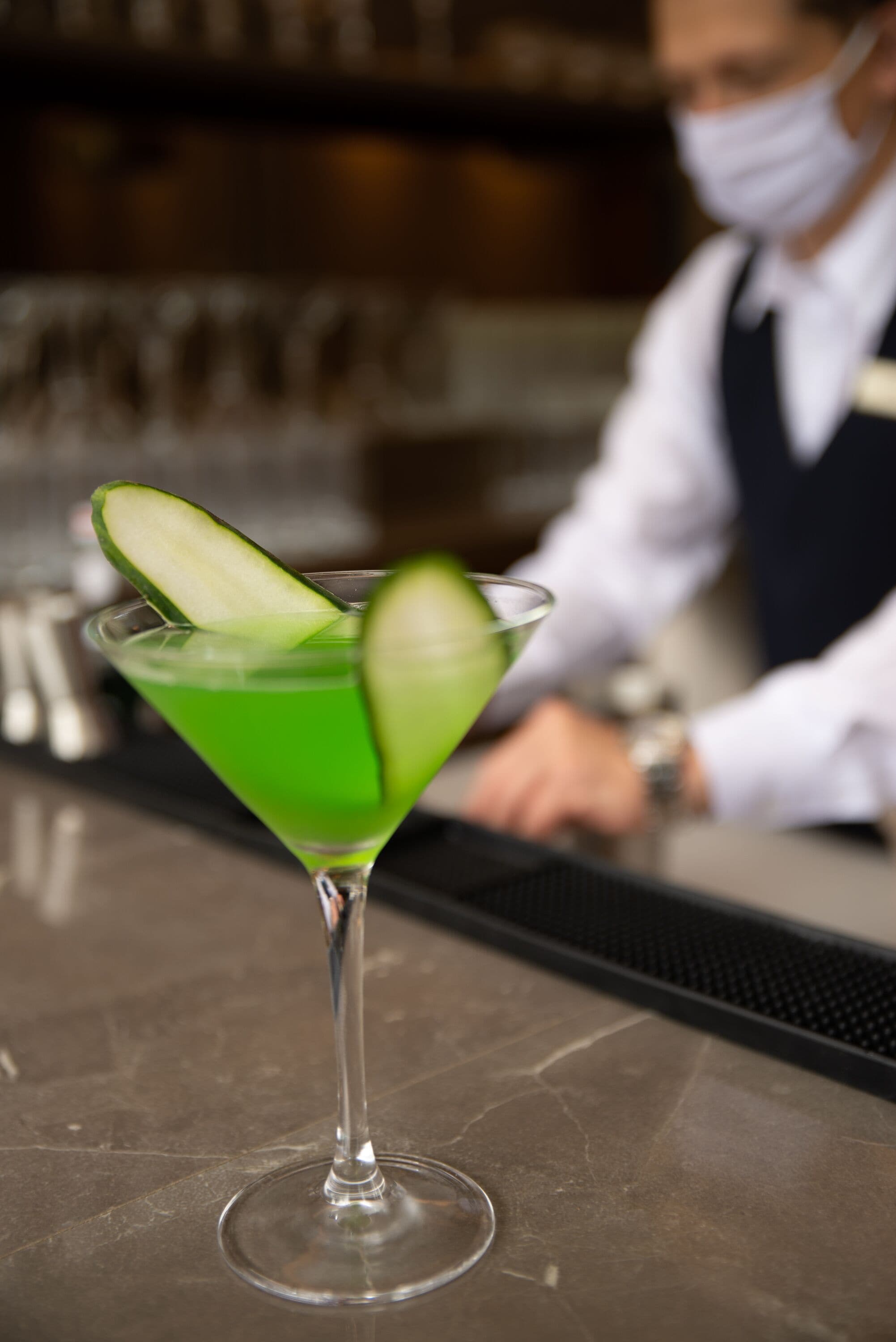 Una copa de martini con una rodaja de lima sobre una barra.