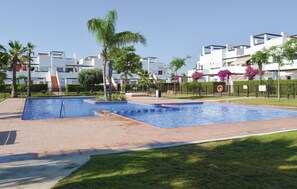 Area piscina con due vasche, circondata da palme e da una recinzione.