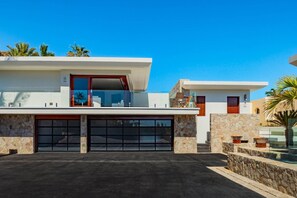A modern two-story house with a garage, stone facade, and a clear blue sky. - Villa in Cabo San Lucas 1034 (Cabo San Lucas)