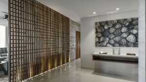 A modern interior with a wooden slat partition, a marble wall, and a large shell-patterned artwork. - Luxury Holiday Penthouse With Majestic Ocean Views, Cabo San Lucas Penthouse 1024 (San José del Cabo)