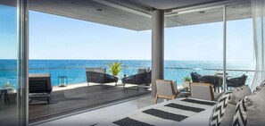 A modern balcony with a view of the ocean, furnished with sofas and chairs, and a dining area with a table and chairs. - Luxury Holiday Penthouse With Majestic Ocean Views, Cabo San Lucas Penthouse 1024 (San José del Cabo)